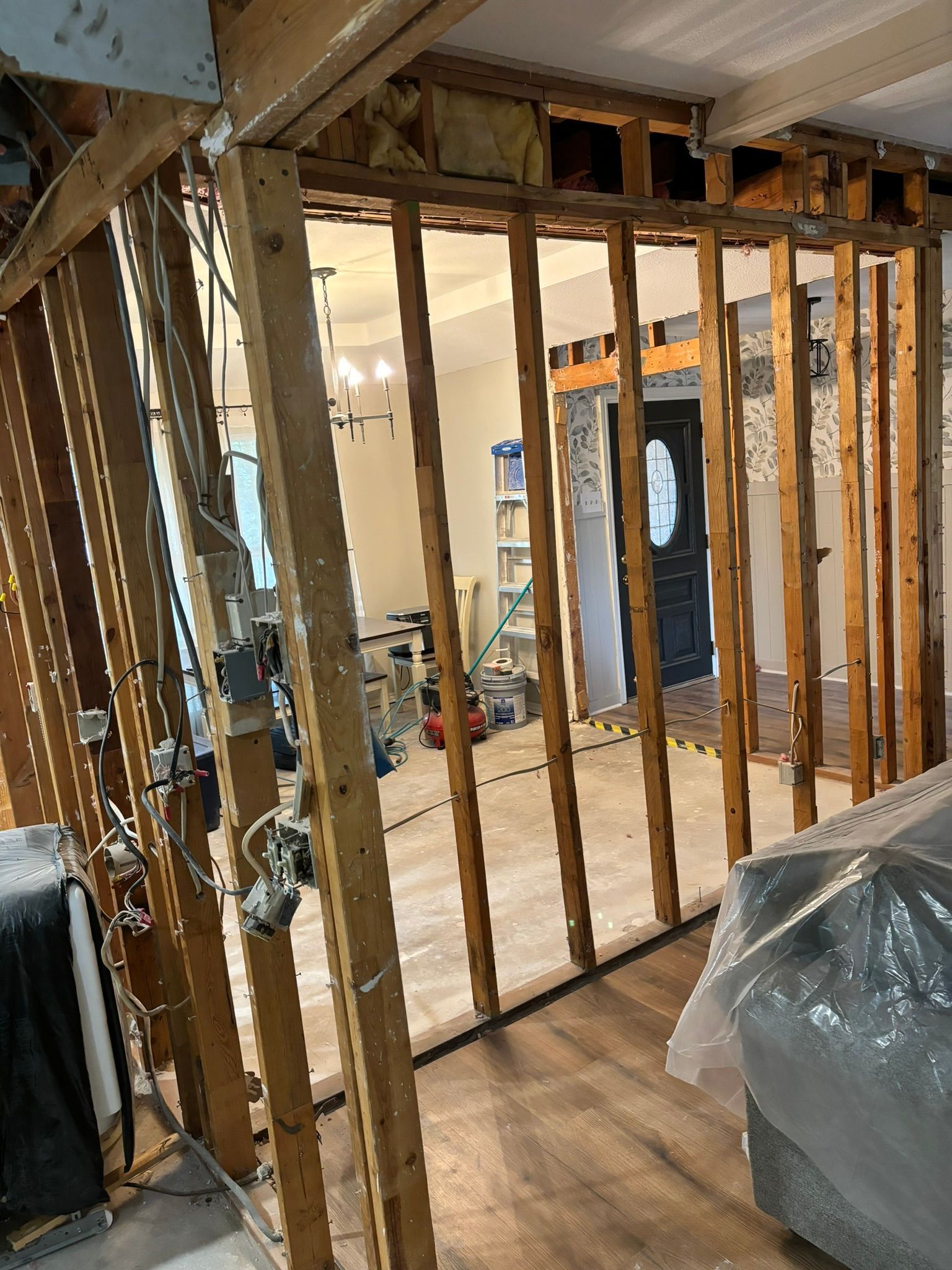 Interior demolition revealing wall studs. Wires, outlets, and insulation are visible.