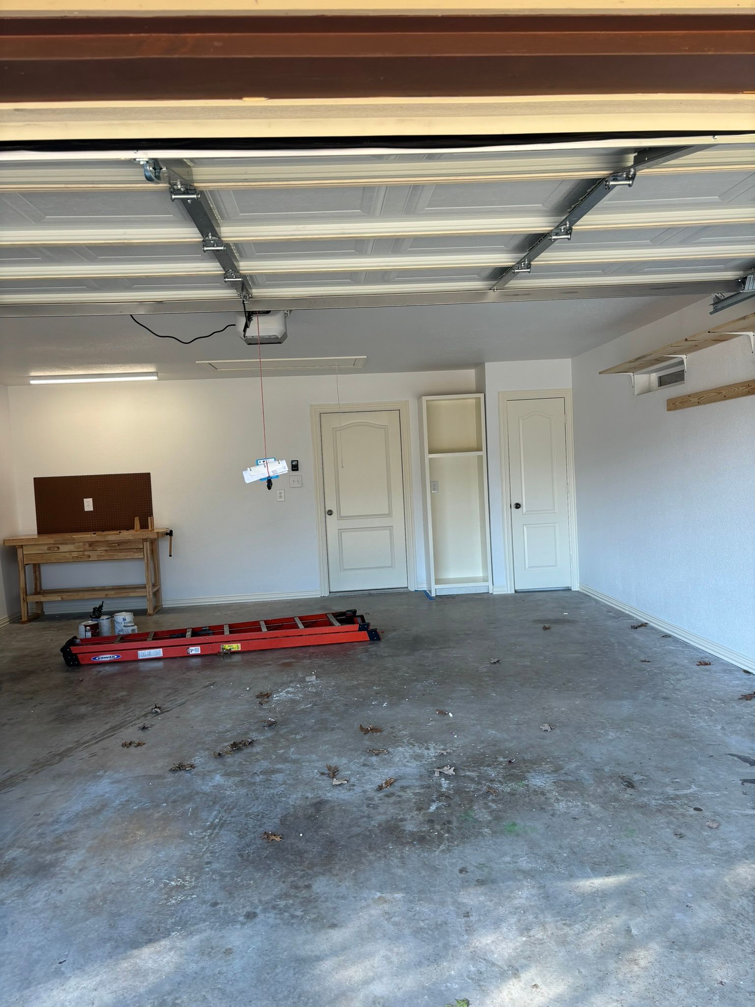 Man on stilts sanding ceiling with a power sander, dust collection hose attached.