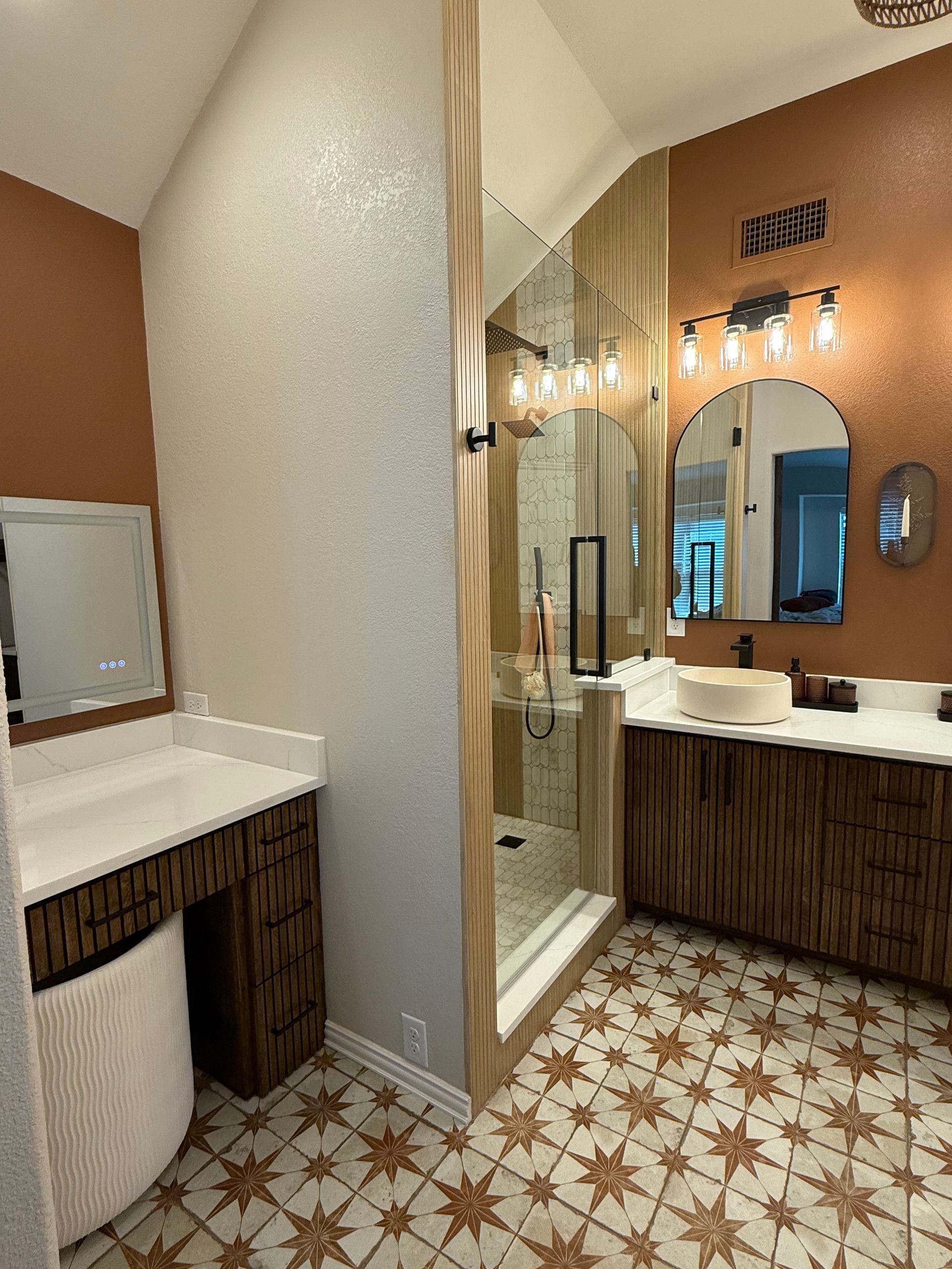 Modern bathroom with white vanity, floating toilet, brown wood flooring, and dark gray walls.