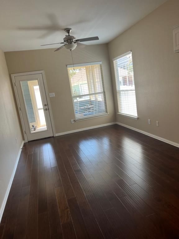 Woman painting a white wall with a roller, standing on a small stool. She wears jeans, a tank top, and an apron.