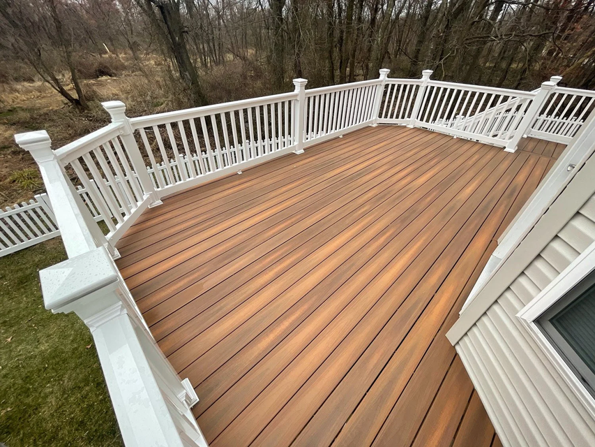 Person kneeling on a porch deck, measuring and aligning brown deck boards with tools nearby.