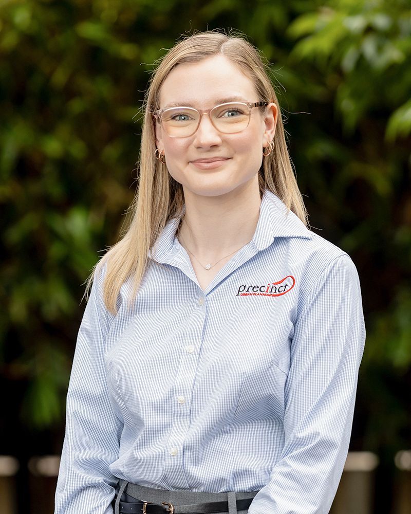 A woman in a blue shirt and brown belt is smiling for the camera.