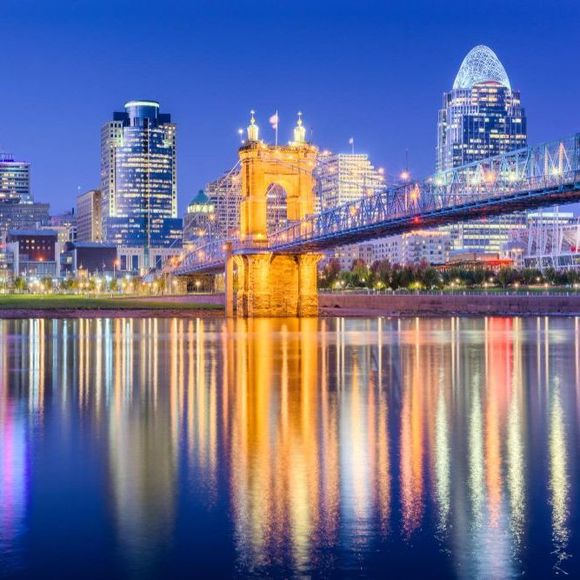 A bridge over a body of water with a city skyline in the background at night.