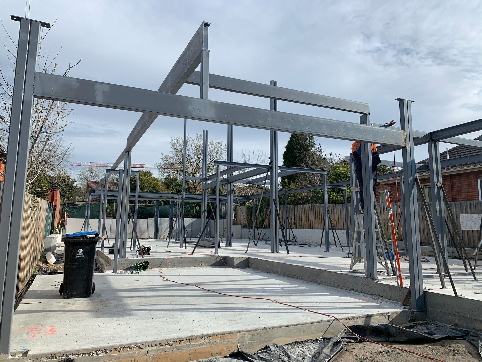 Steel frame of a building under construction; concrete foundation; blue sky in Melbourne.