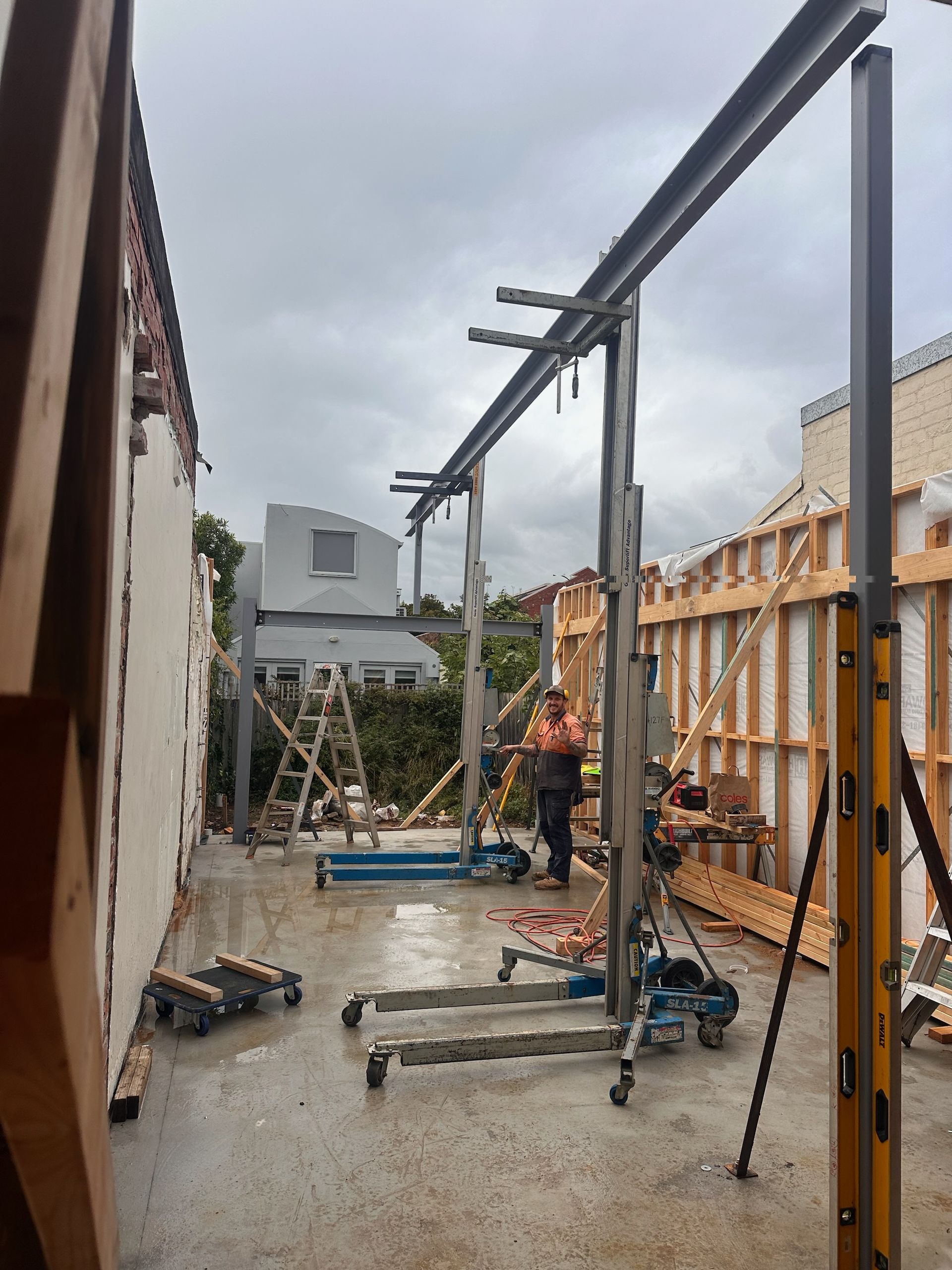 Steel construction site with workers using lifts to build a metal structure in Melbourne.
