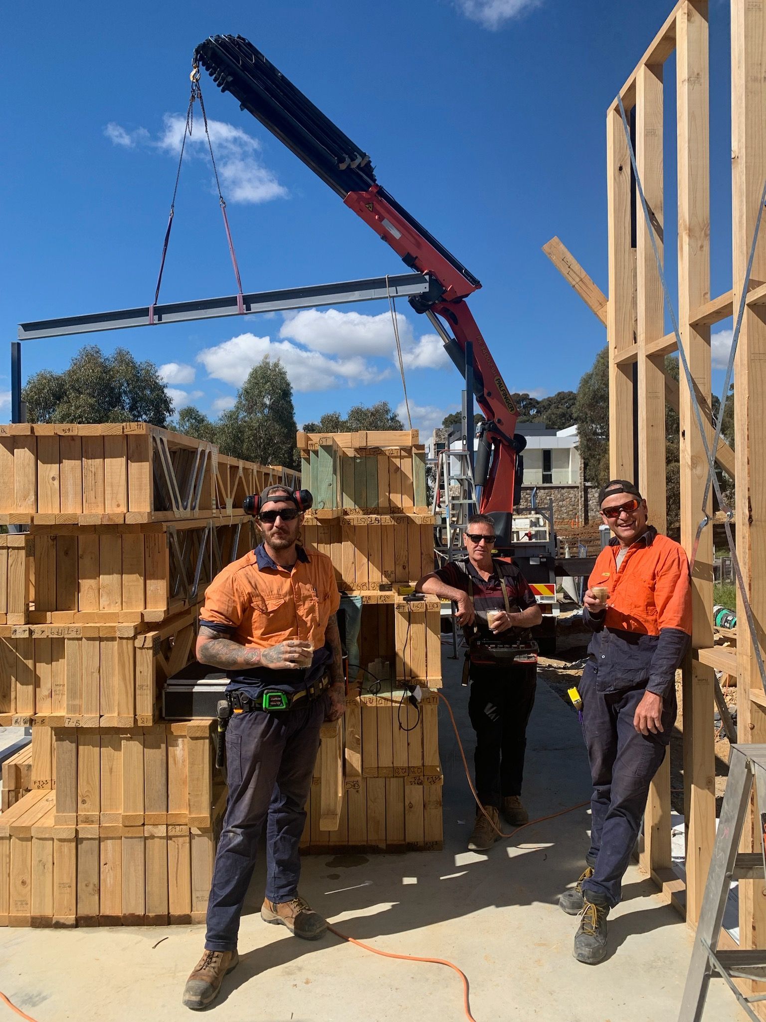 Steel construction workers pose near a crane and building framework in Melbourne.