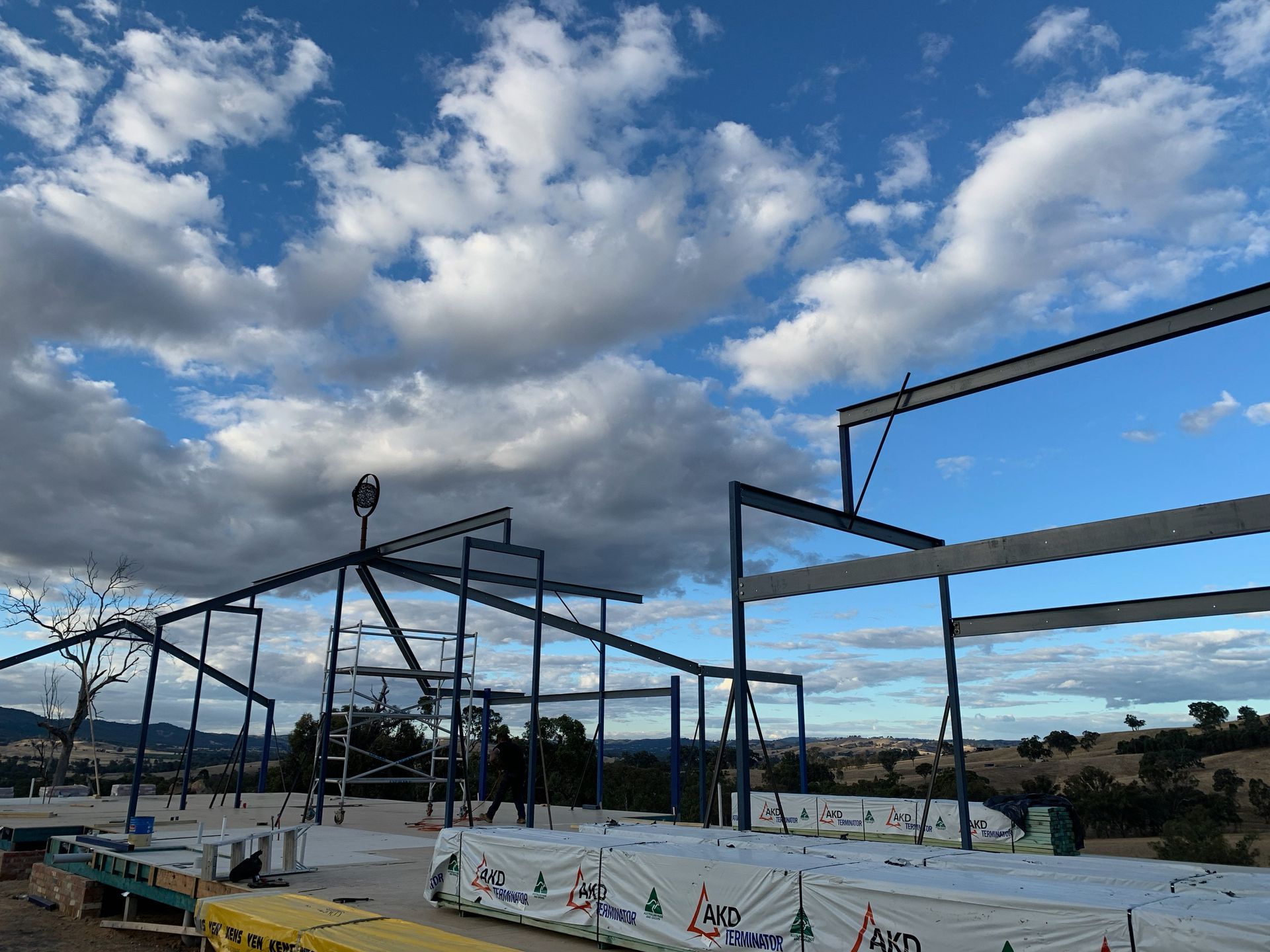 Construction site with blue steel frame against a cloudy sky.