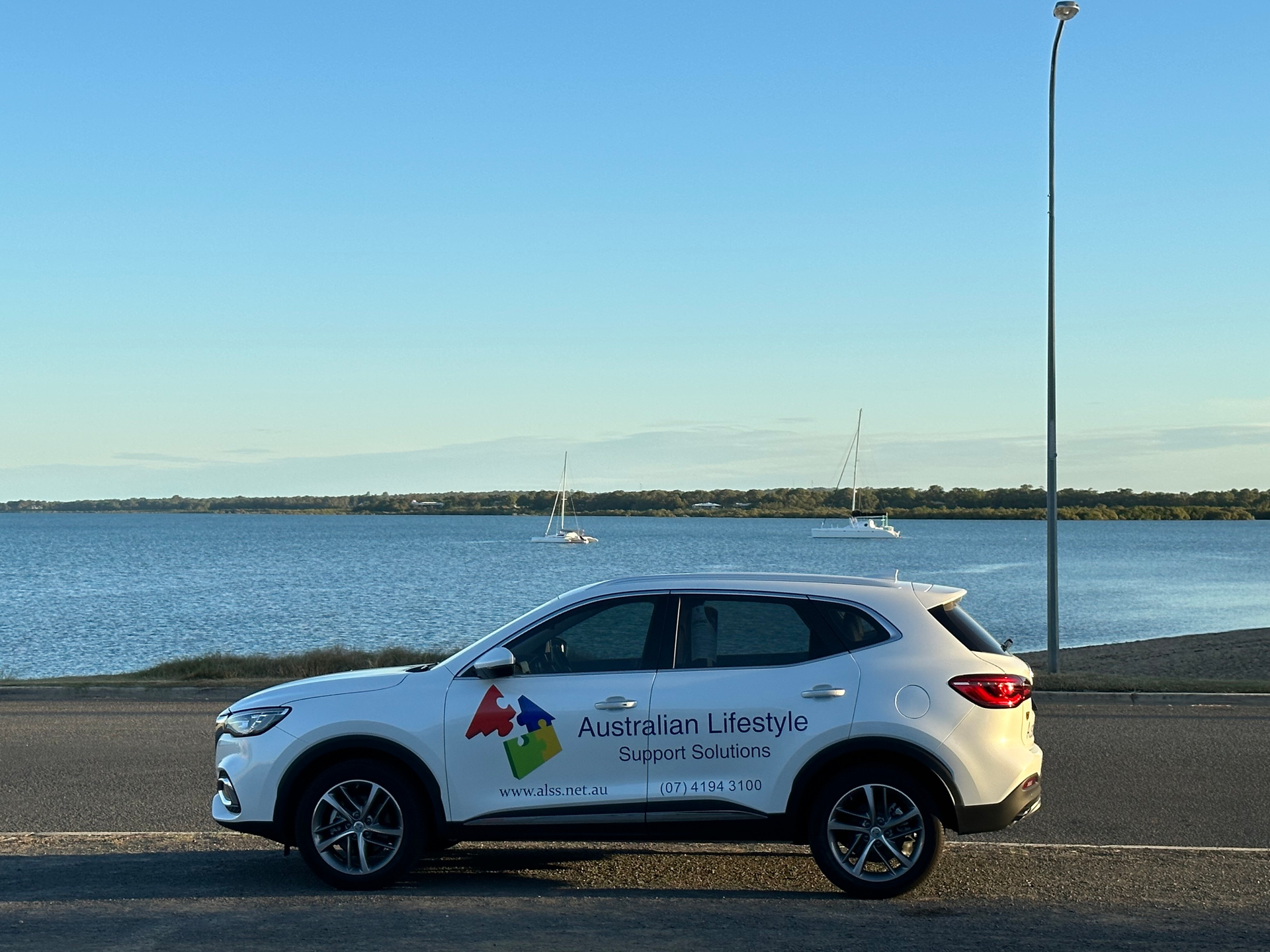 Happy young family of three smiling while spending free time outdoors - NDIS in Urangan, QLD