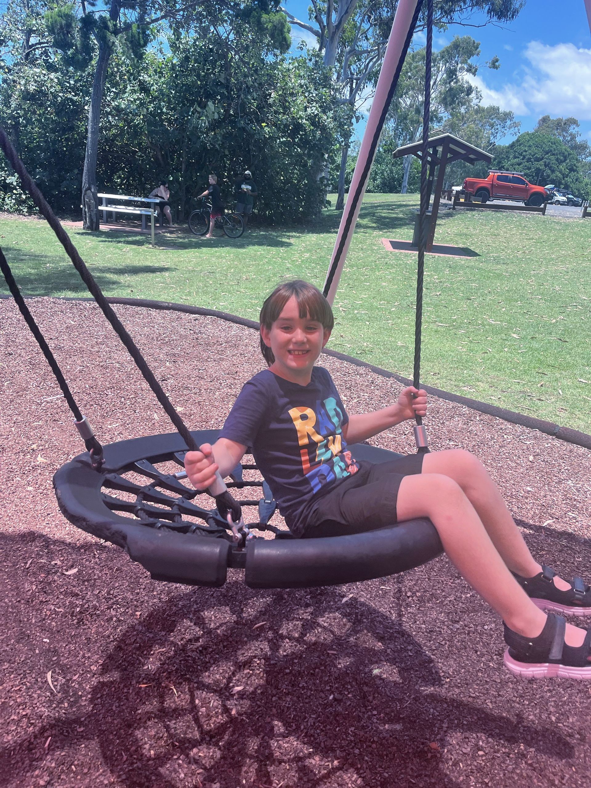 A boy with disability on a swing at the park - NDIS in Urangan, QLD