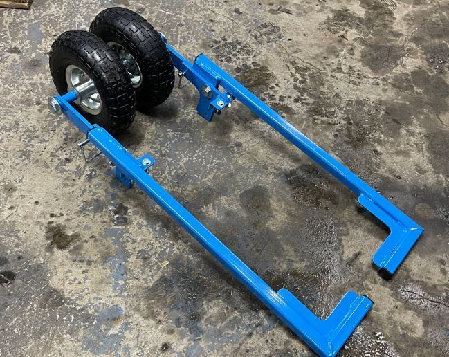 A blue cart with two wheels is sitting on a concrete surface.