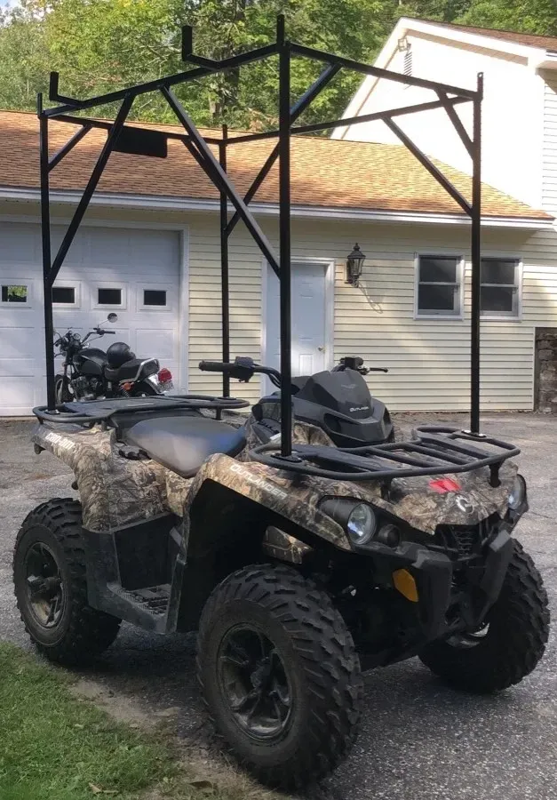 An atv is parked in front of a house with a canopy attached to it.