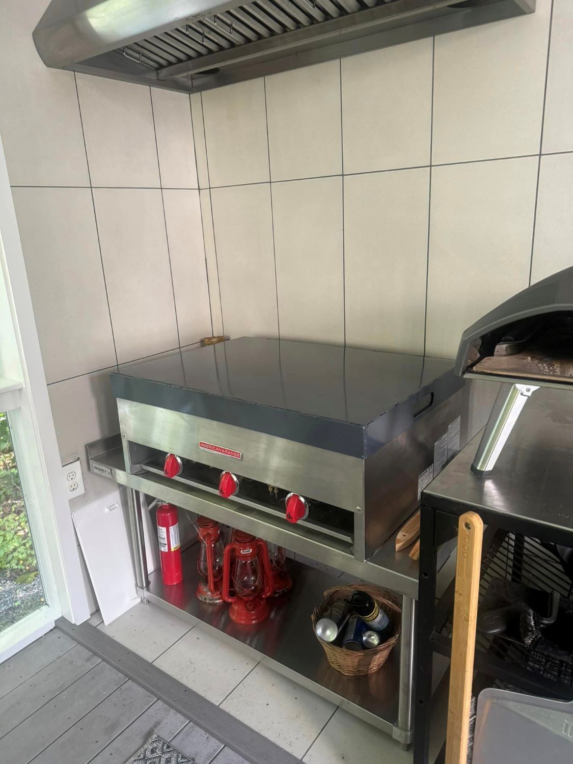 A kitchen with a stove and a shelf with a fire extinguisher on it.