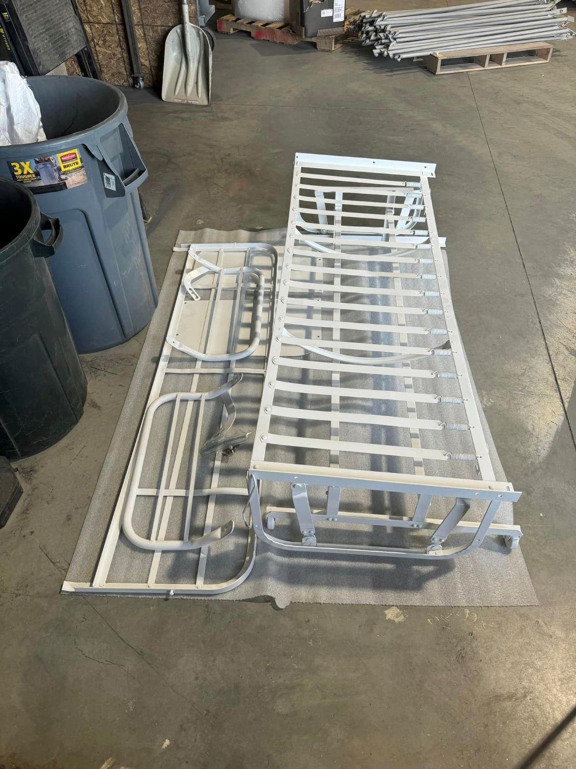 A white metal bed frame is sitting on top of a concrete floor.