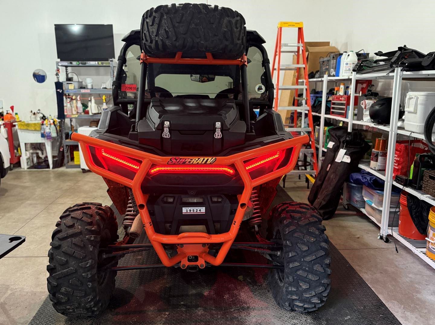 An orange atv is parked in a garage.