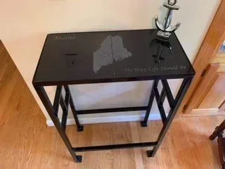 A small table with a map of maine on it is sitting on a wooden floor.