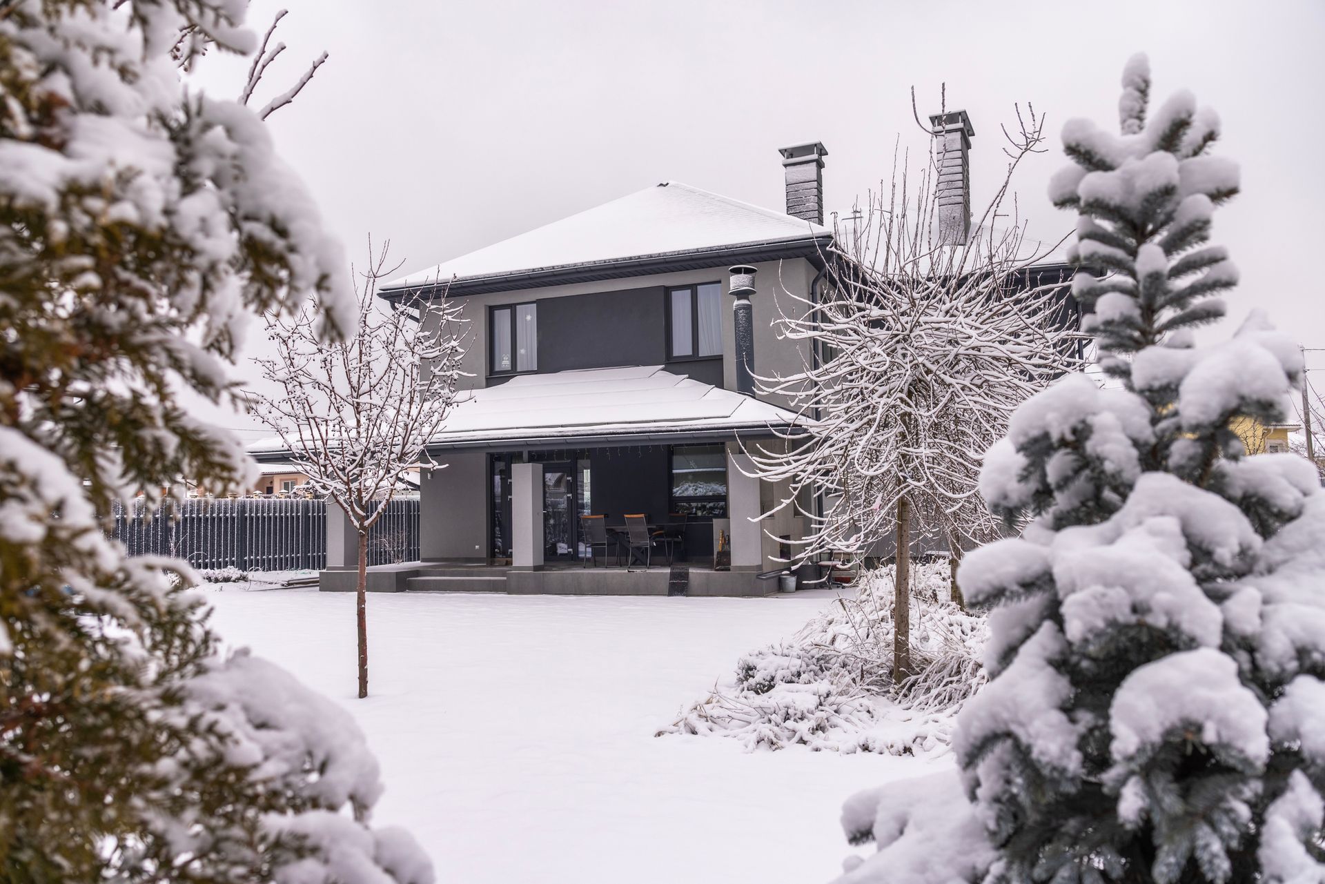 Snow-covered house and garden with trees in a quiet winter scene