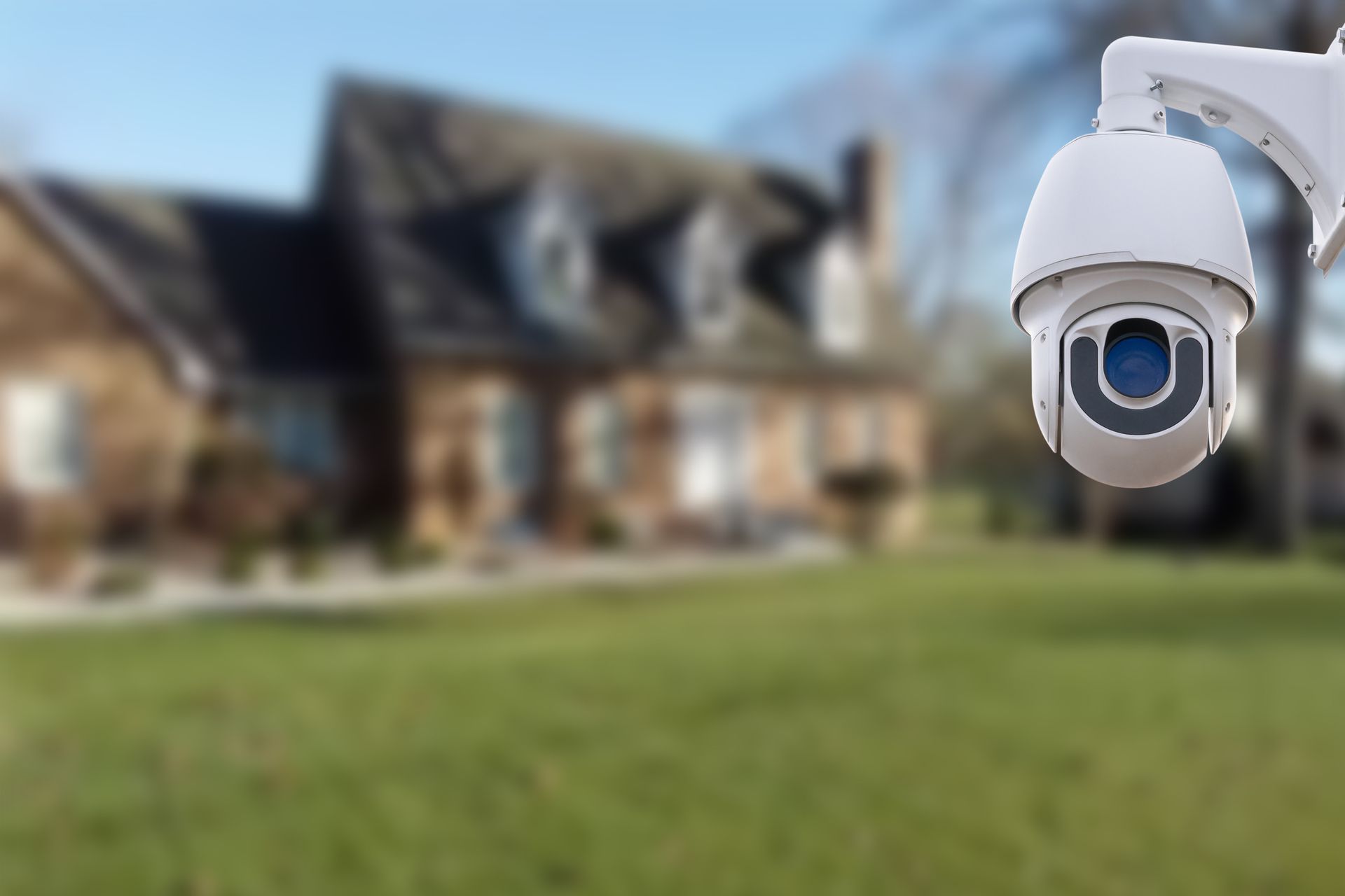 Outdoor security camera overlooking a blurred suburban house and lawn