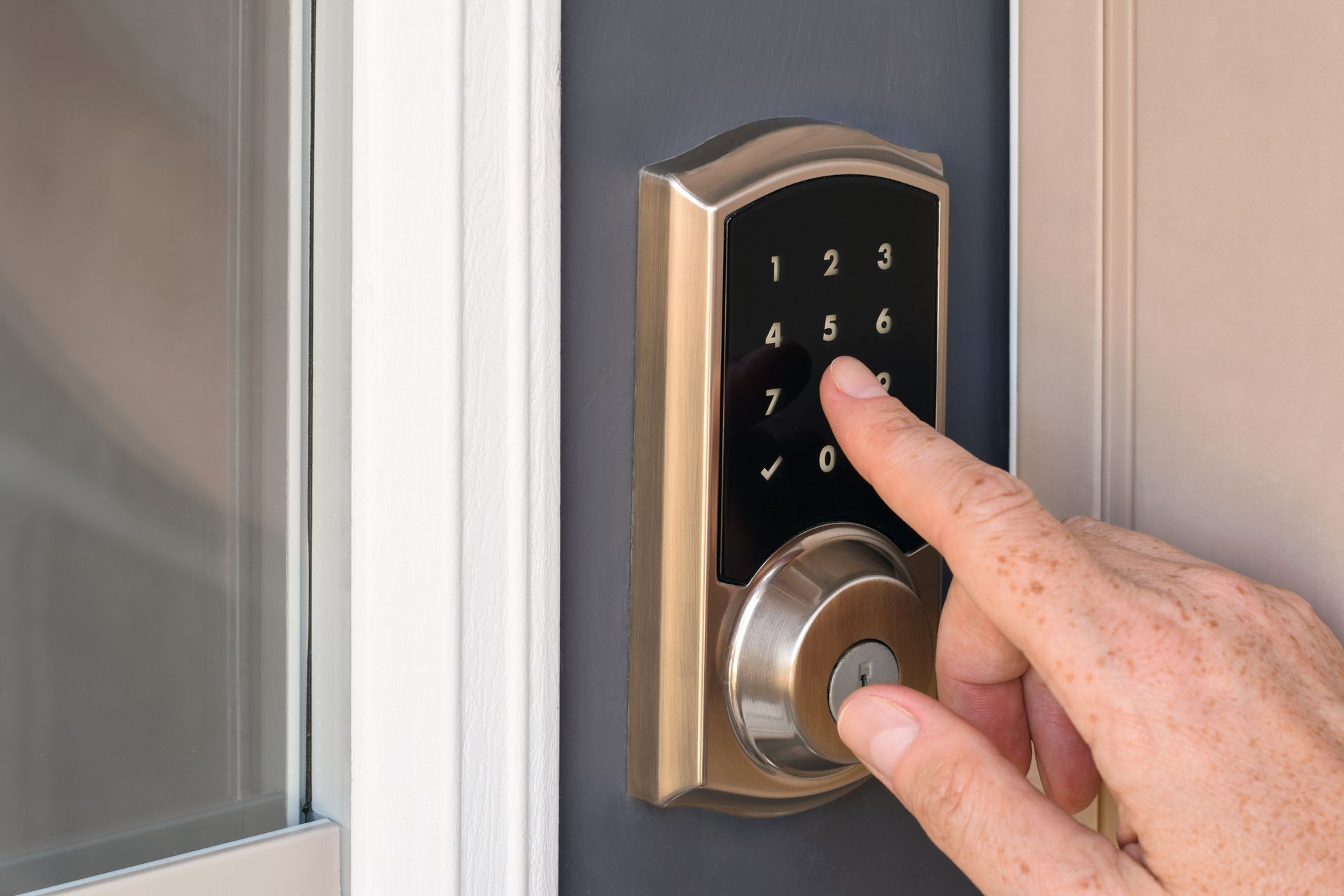 Hand pressing a lit keypad on a front door lock
