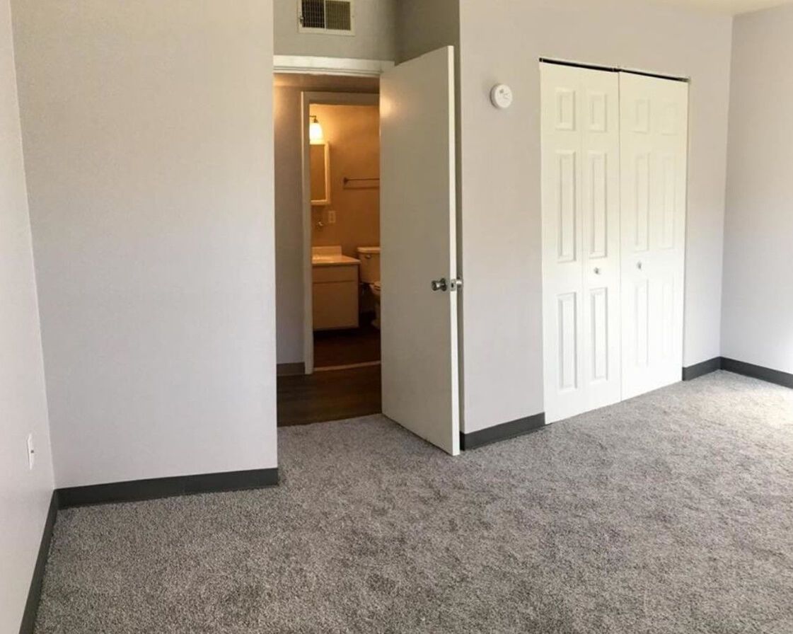 An empty bedroom with a closet and a bathroom.