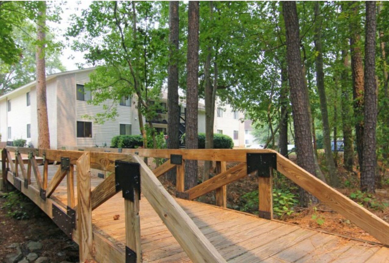A wooden bridge leading to a house in the woods