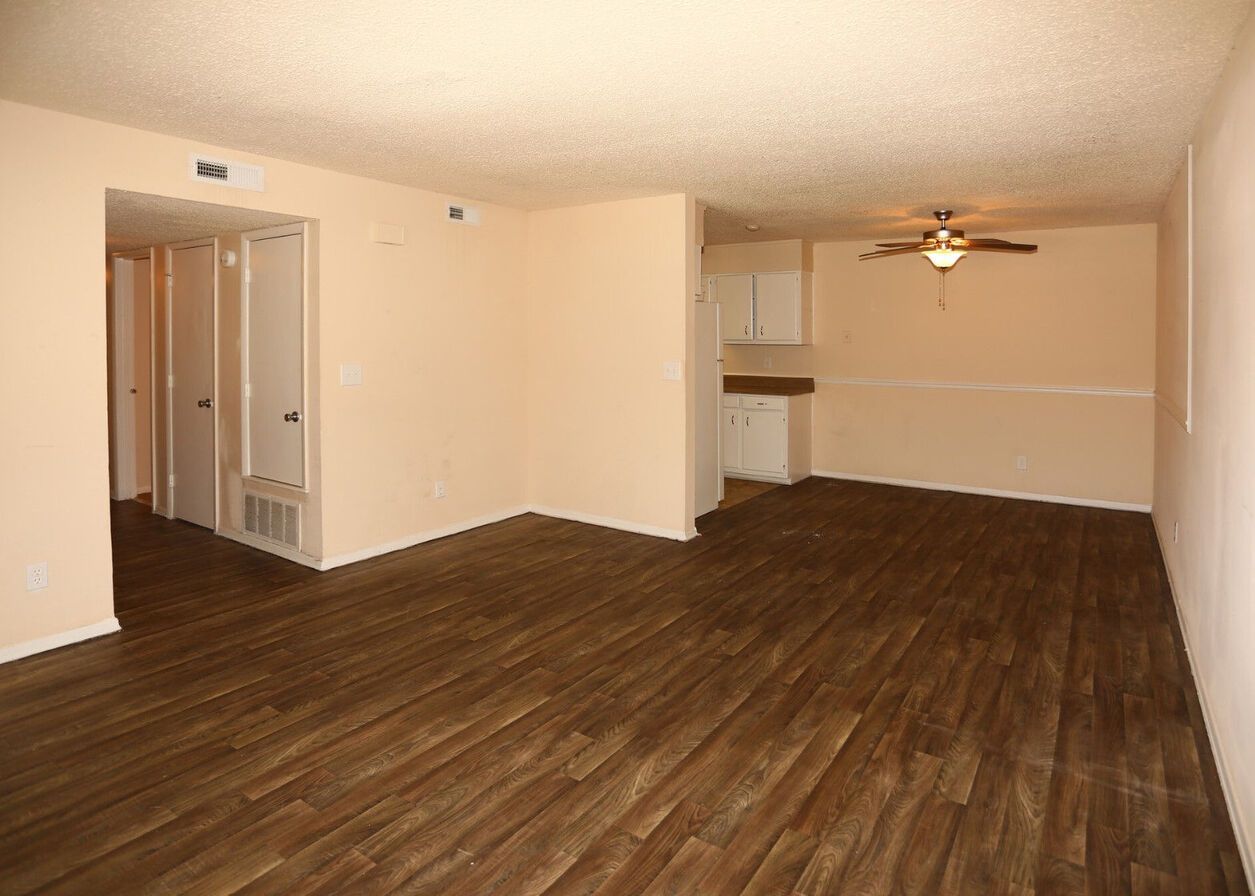 An empty living room with hardwood floors and a ceiling fan.