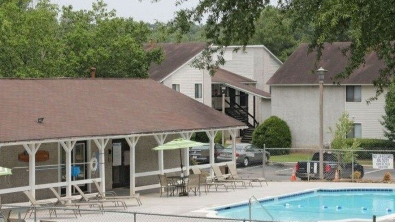 A swimming pool in front of a building with umbrellas