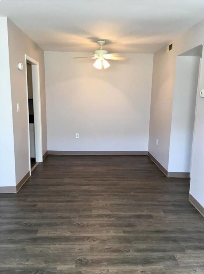 An empty living room with hardwood floors and a ceiling fan.