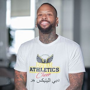 Man with tattoos smiles, wearing white 