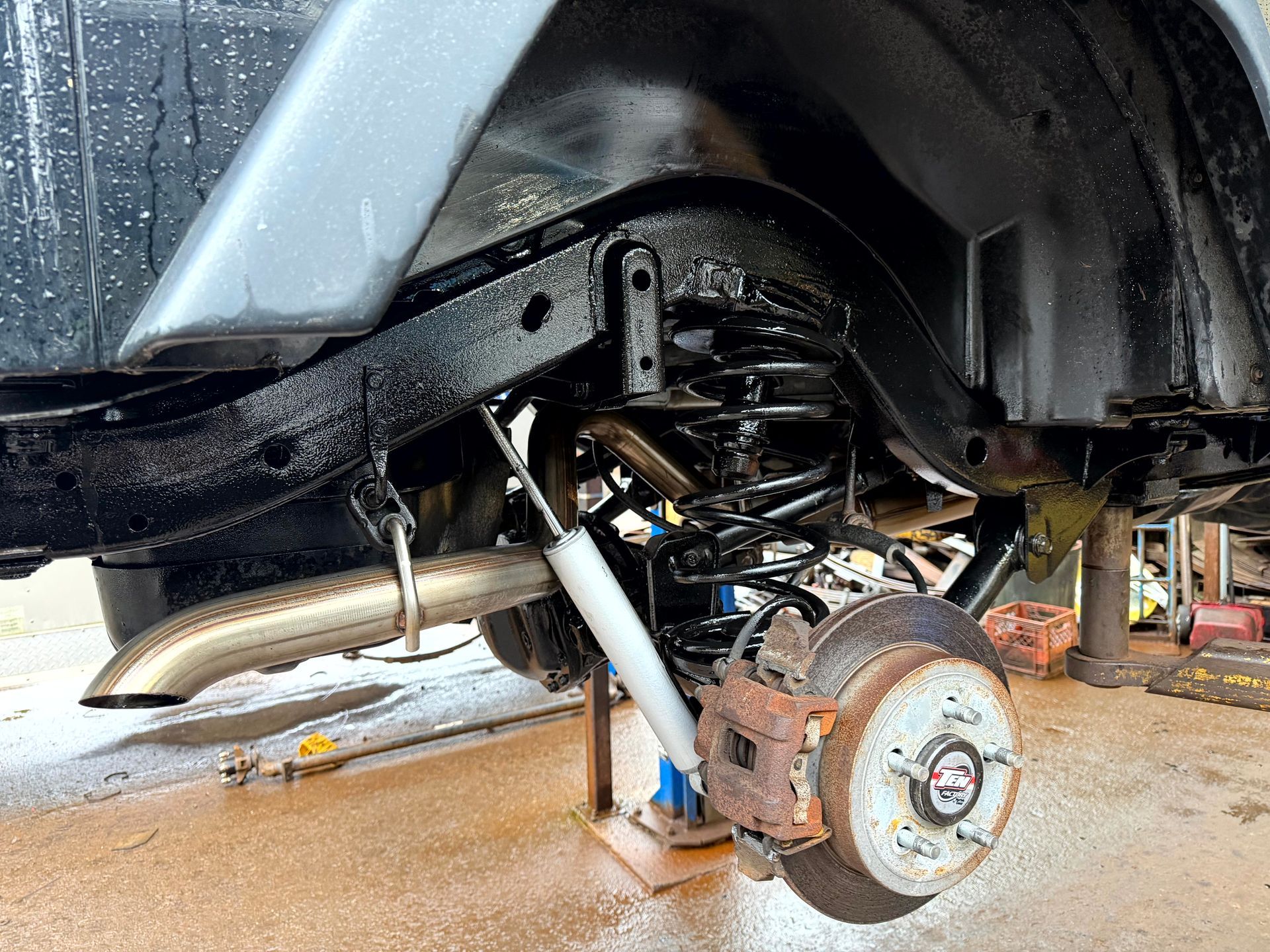 Black painted Jeep frame with suspension and brake parts.