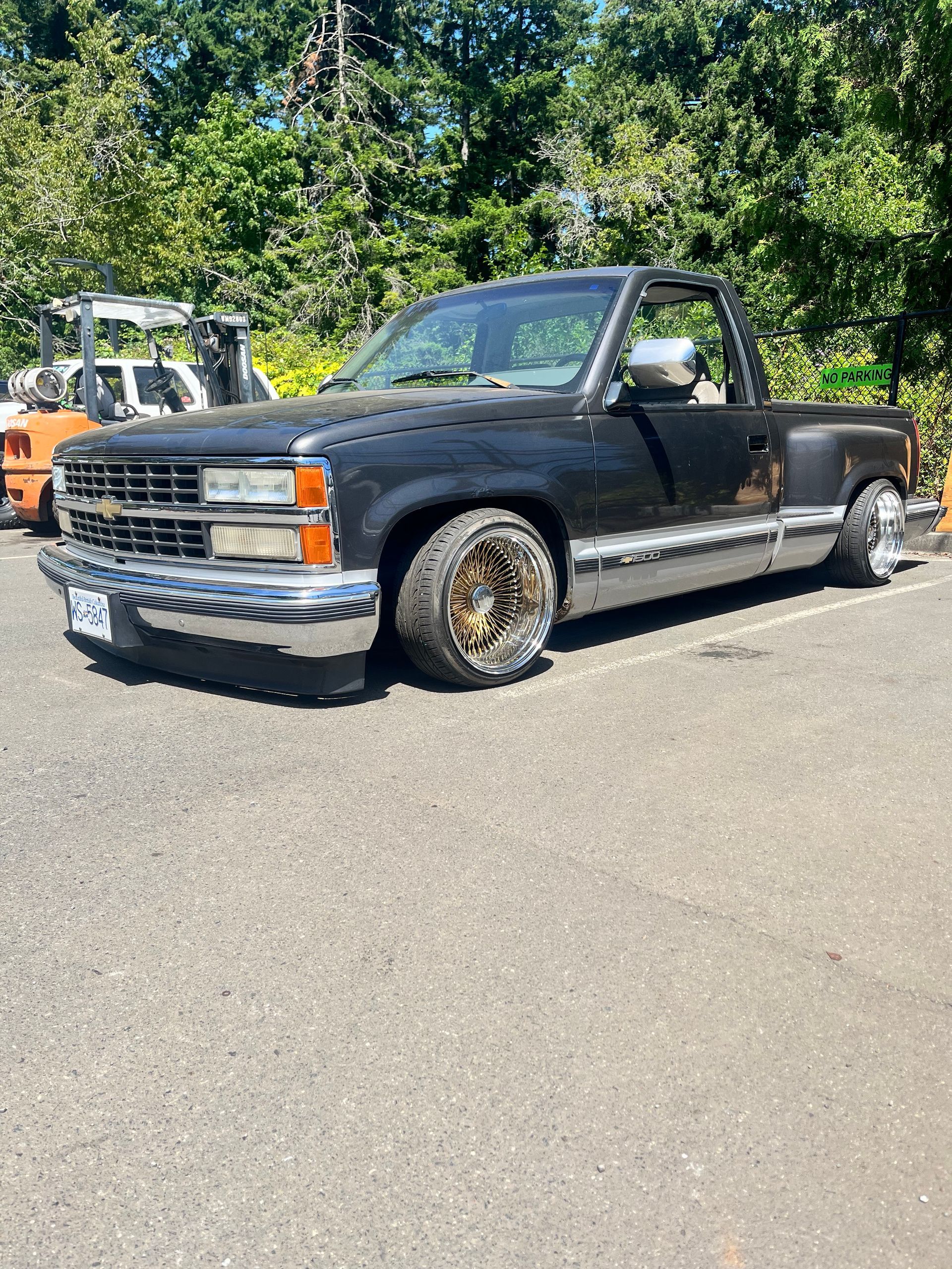 Black Chevrolet pickup truck with custom gold wheels, parked outdoors.