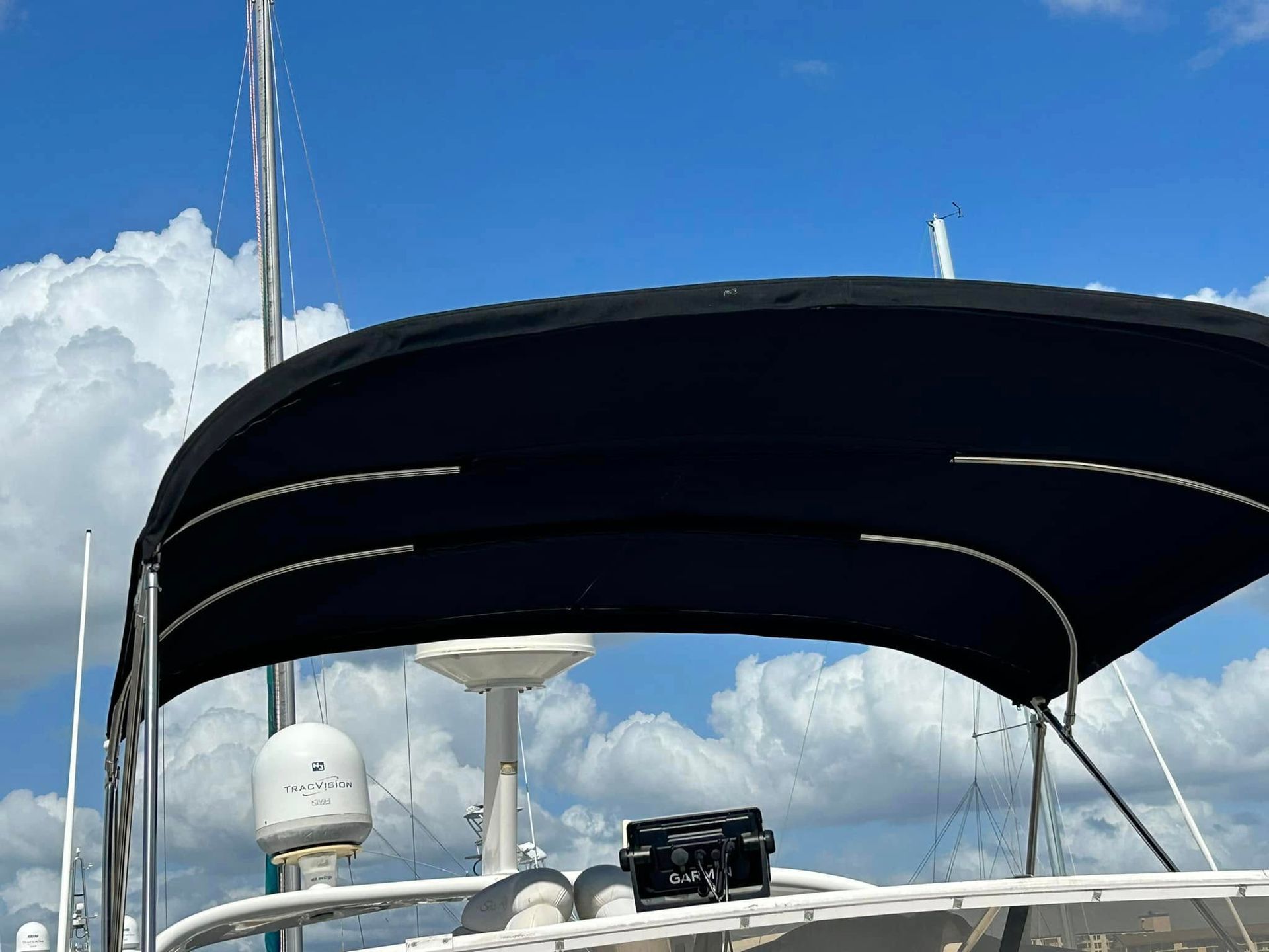 Black boat bimini top against a blue sky with white clouds.