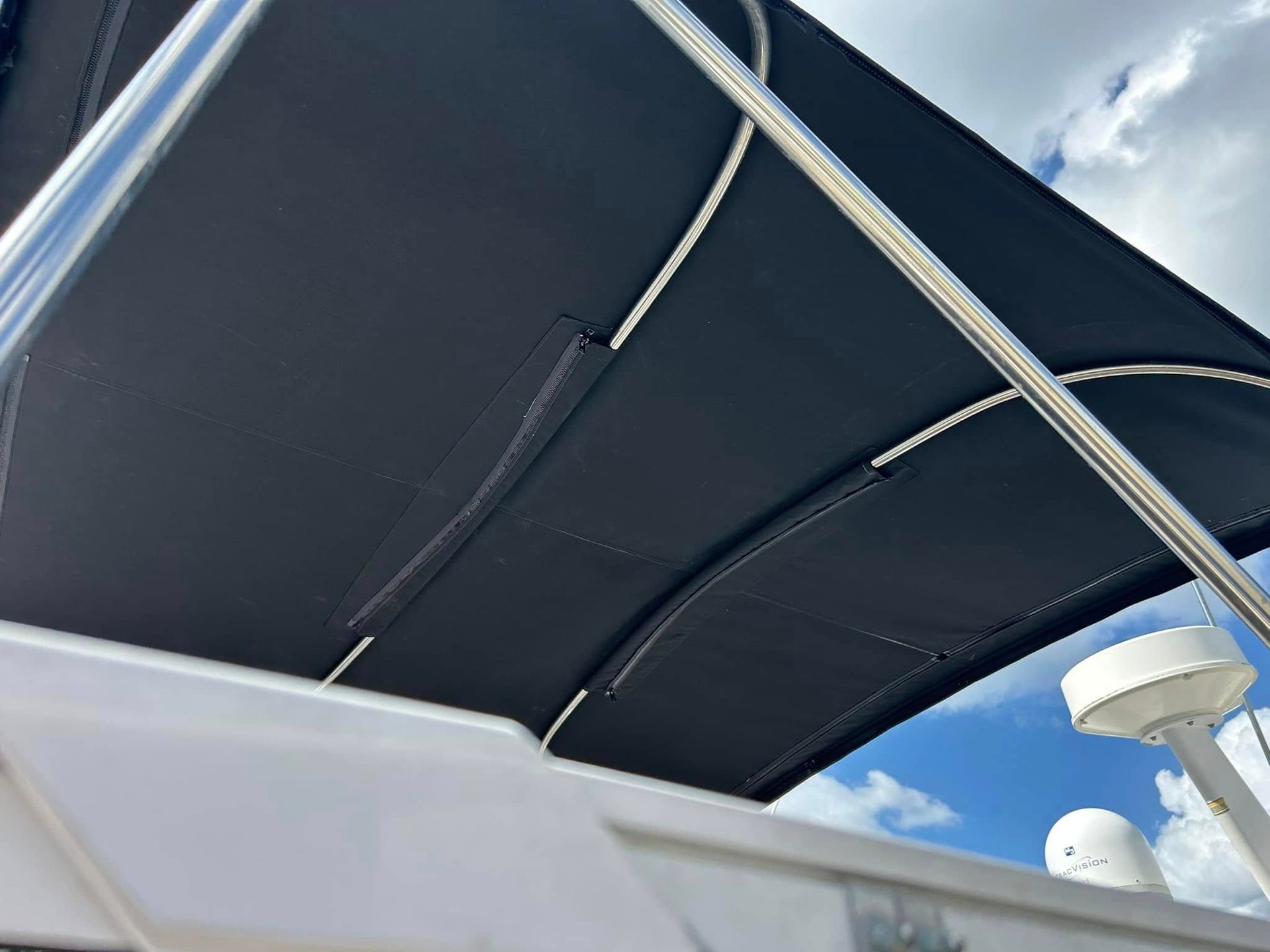 Black boat awning, stainless steel frame, against a blue sky.