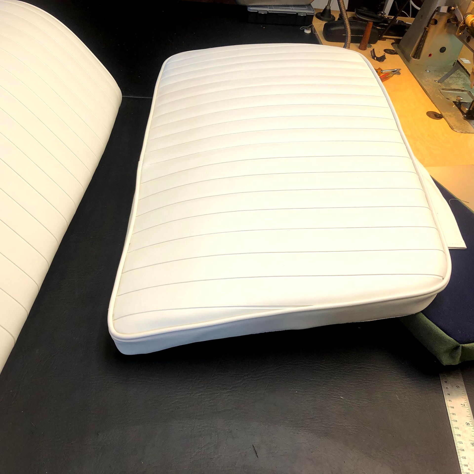 White upholstered boat cushion with horizontal stitching on a black surface.