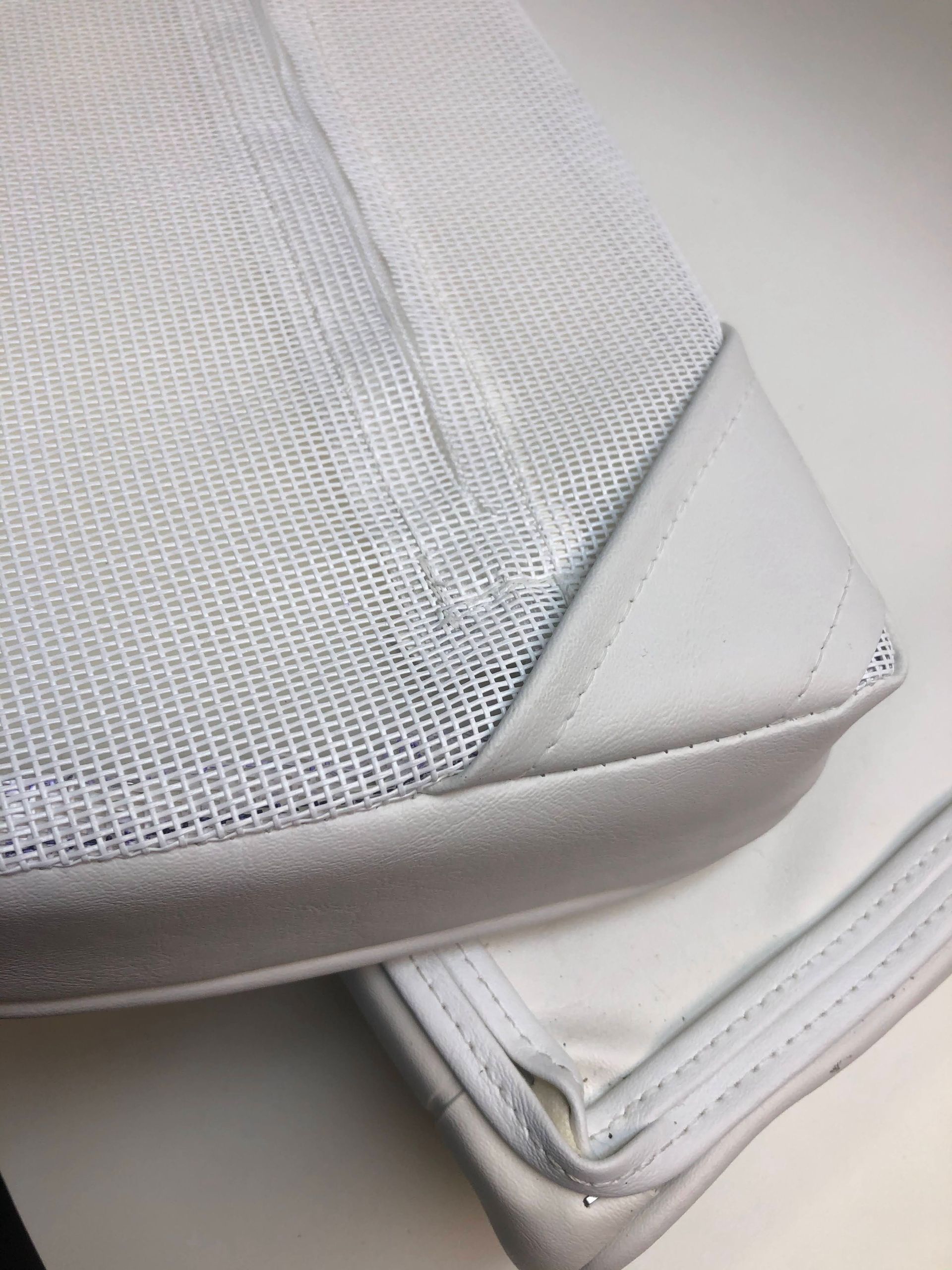 Two white, rectangular mesh bags with leather trim, stacked at an angle, on a white surface.