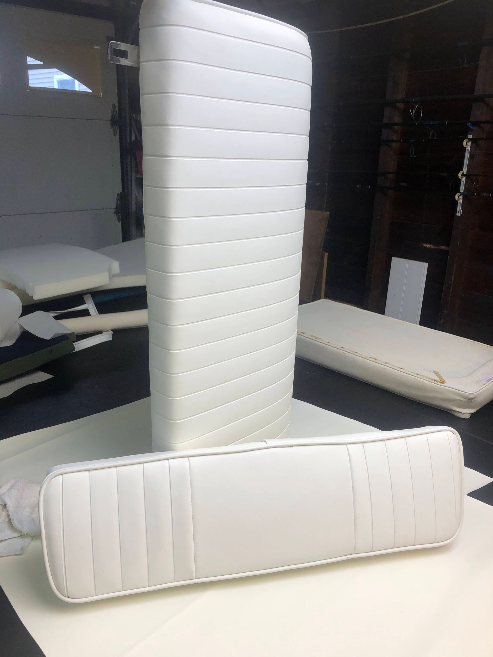 White boat seats, rectangular with horizontal stitching, against a black and white checkered floor, in a garage.