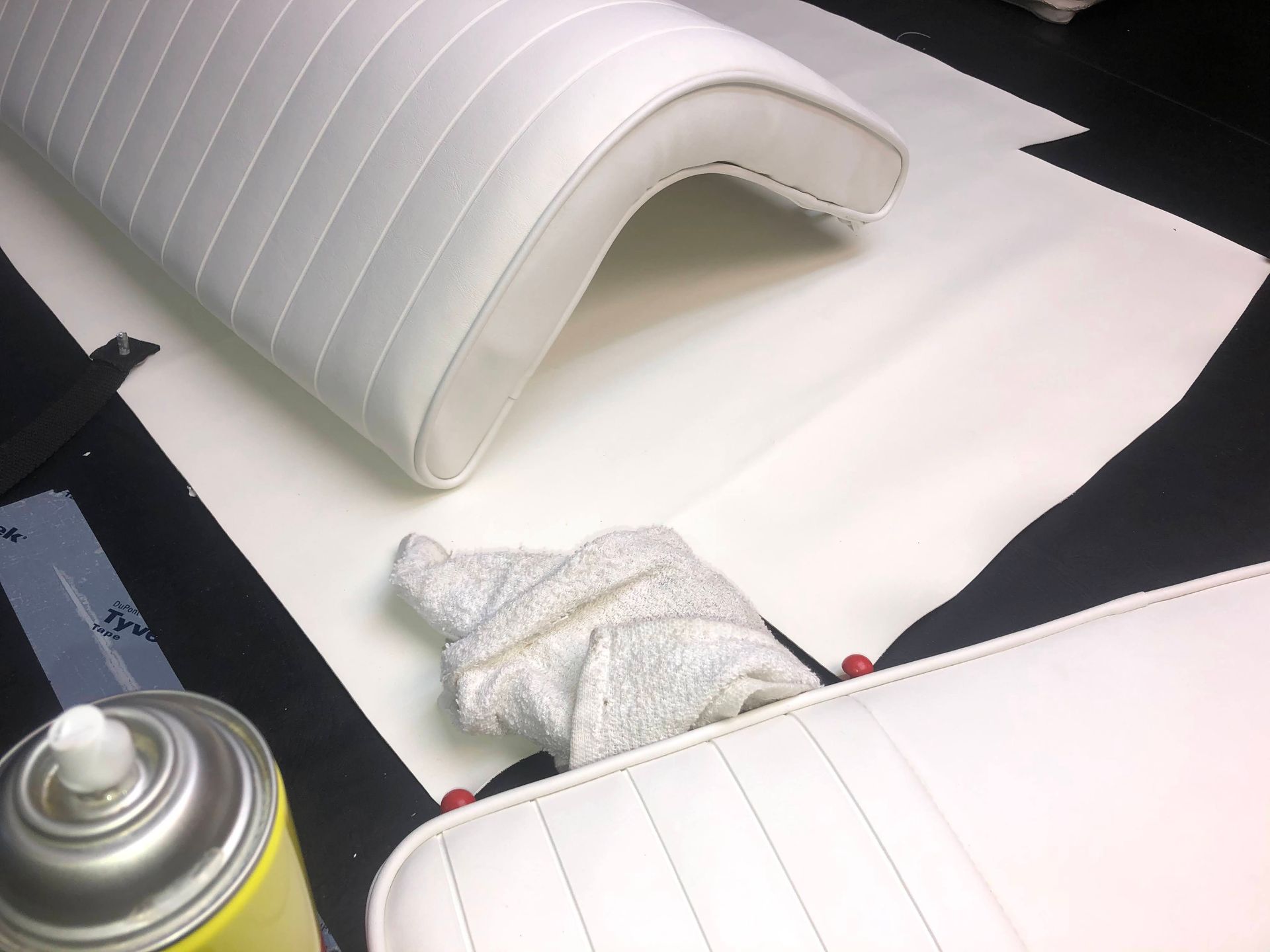 White boat seats and a cloth with spray can on a table.