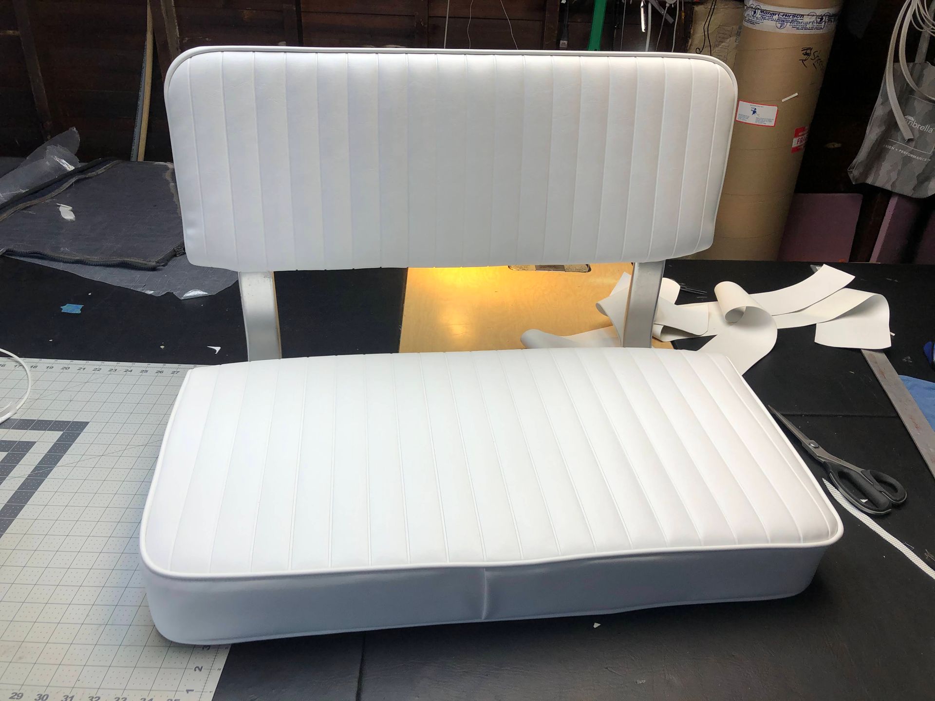 White boat seat with a cushioned back and bottom, on a table.