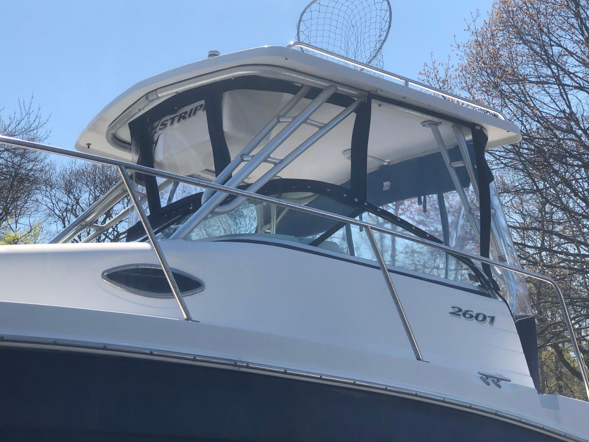 White boat with a cabin; clear windshield, black frame, and a net on top.