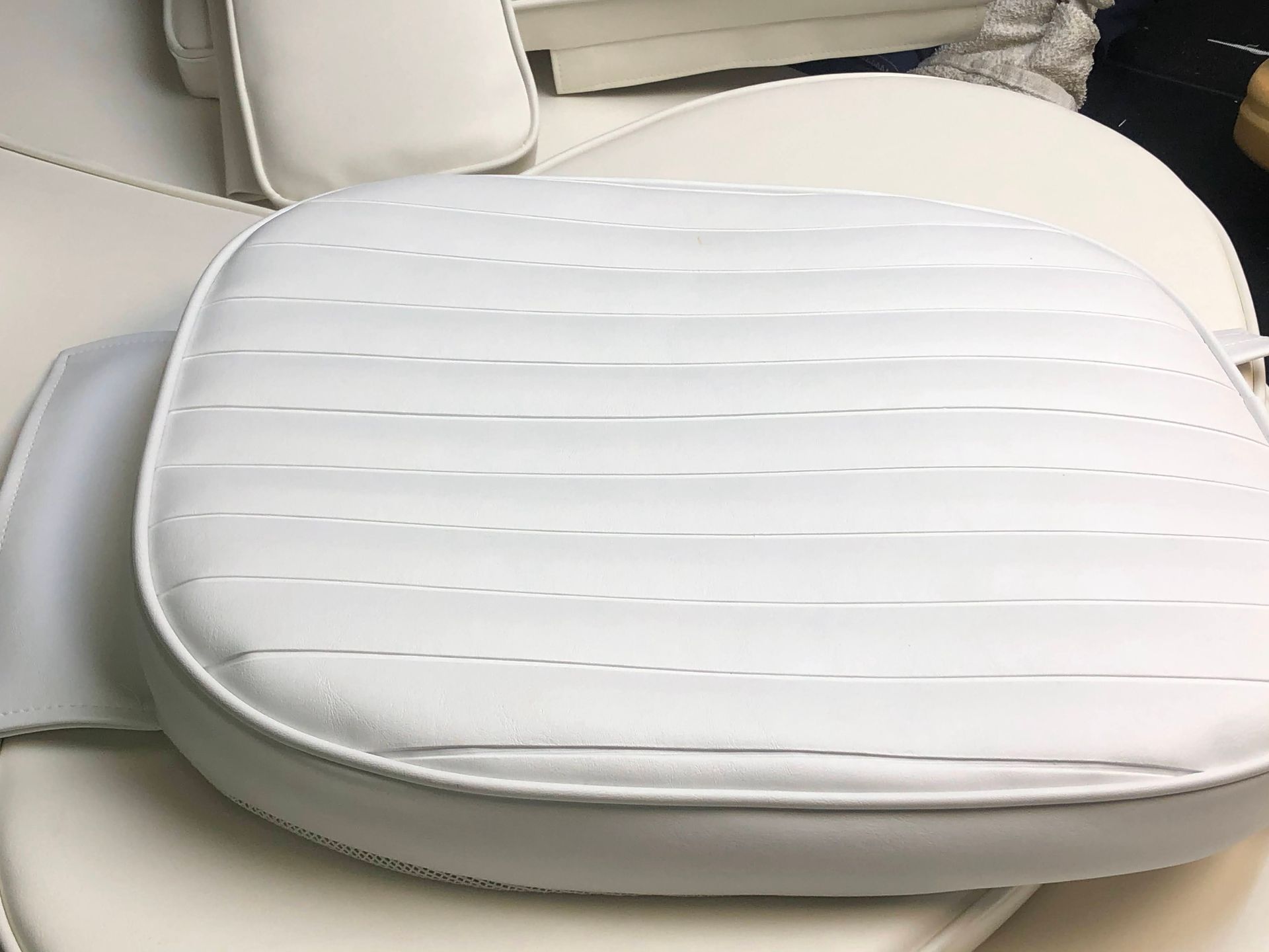 White boat cushion with horizontal stitching, lying on other boat cushions.