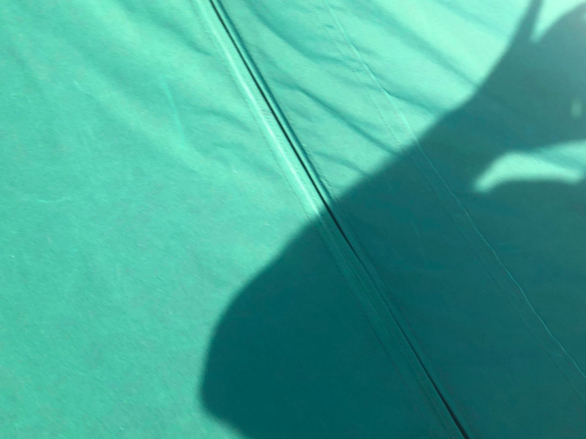 Shadow of a hand and arm on a teal fabric.