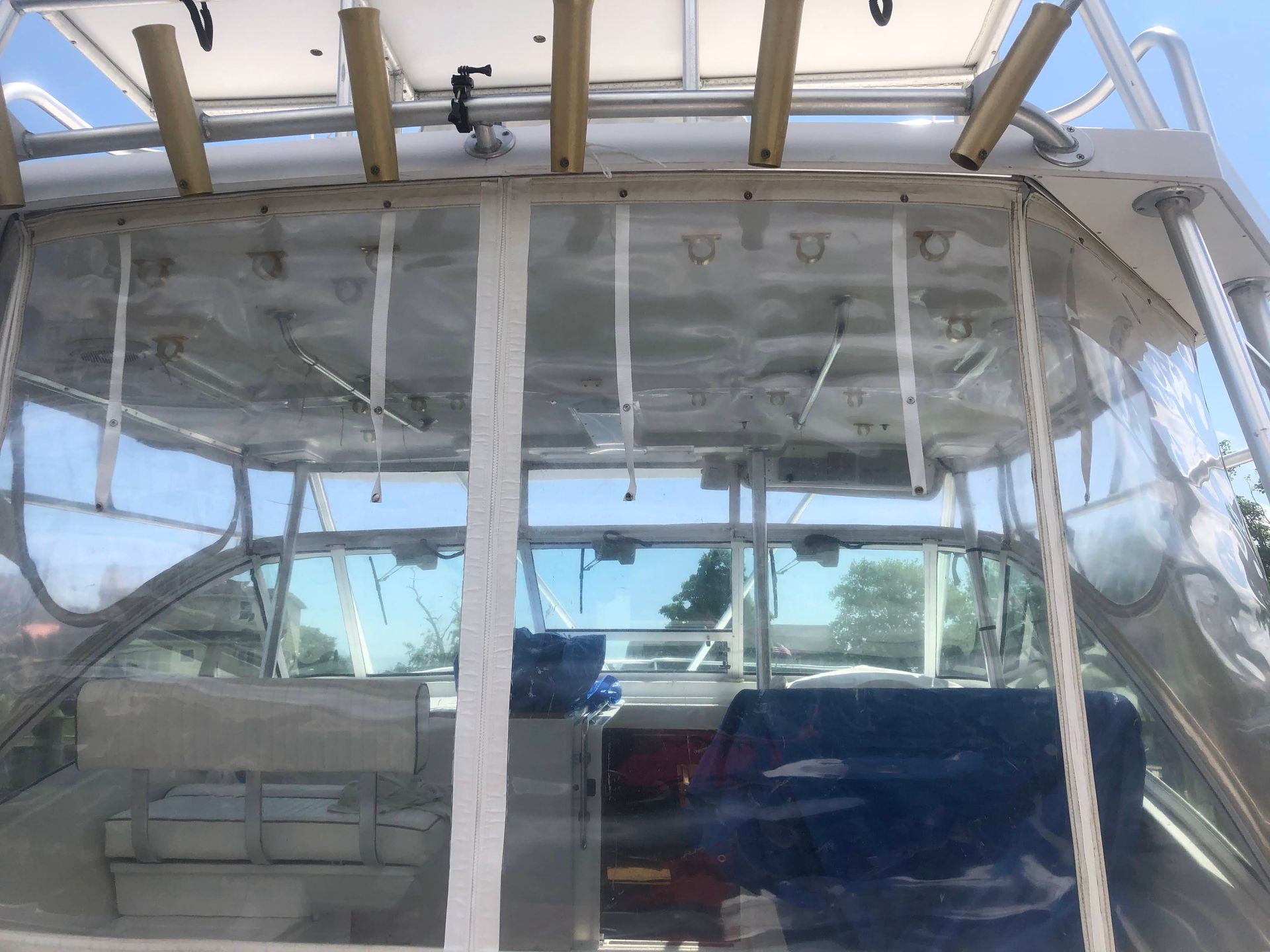 Boat interior with clear plastic enclosure, white framing, blue seating, and instrument panel.