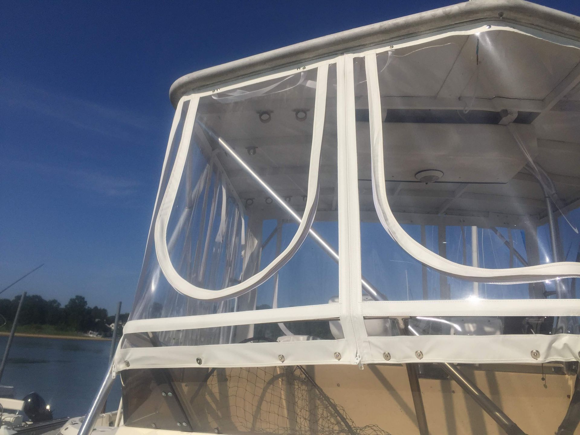 Clear boat enclosure with white trim on a boat deck, blue sky background.