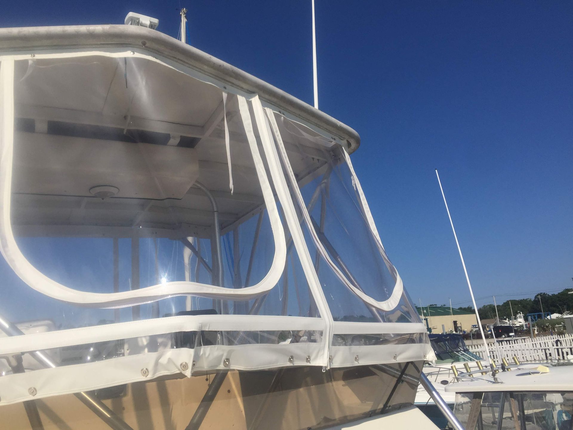 Boat cabin with clear plastic windows and a white frame against a blue sky.