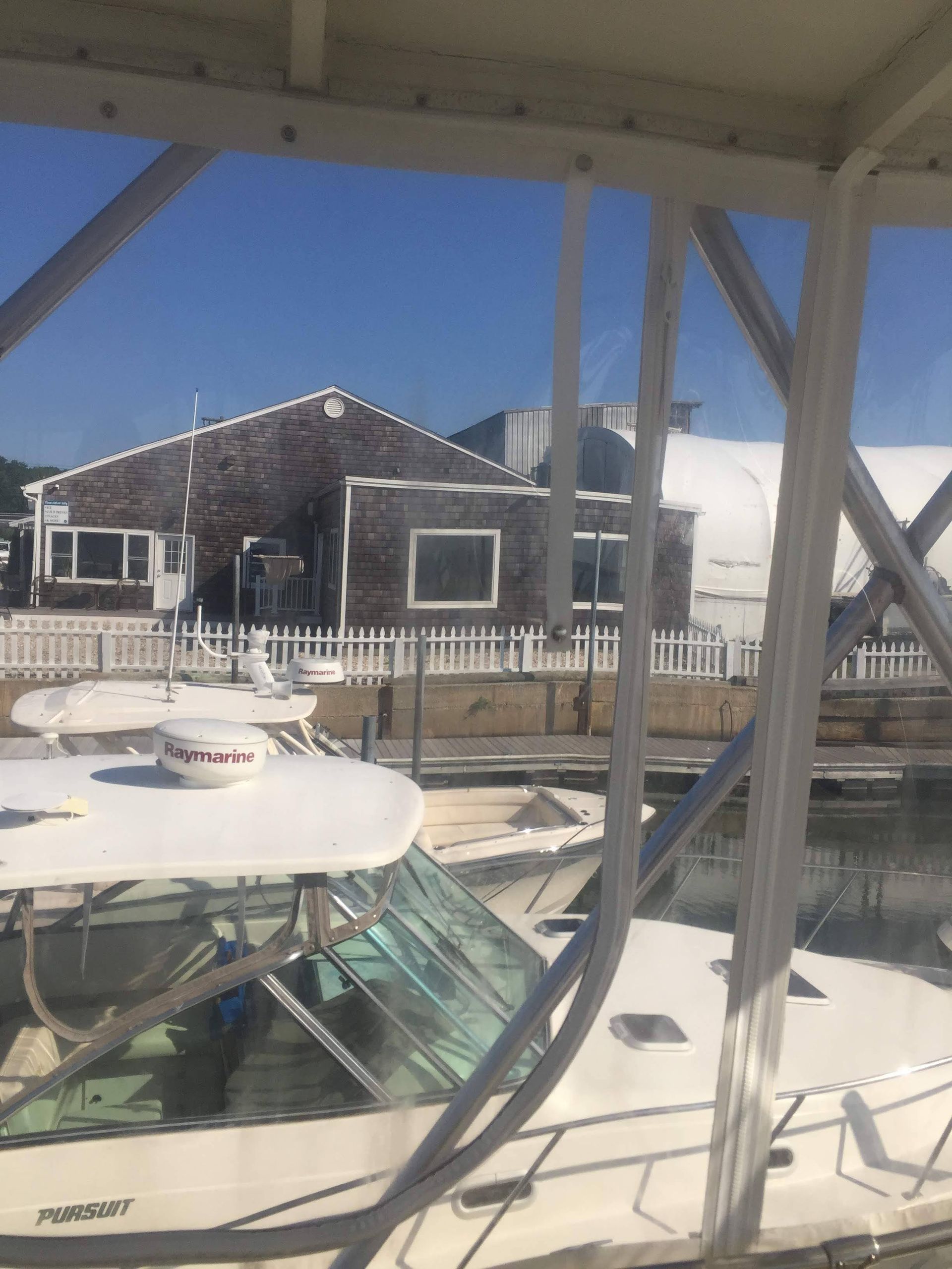 Boats docked at harbor, weathered building in background, blue sky.