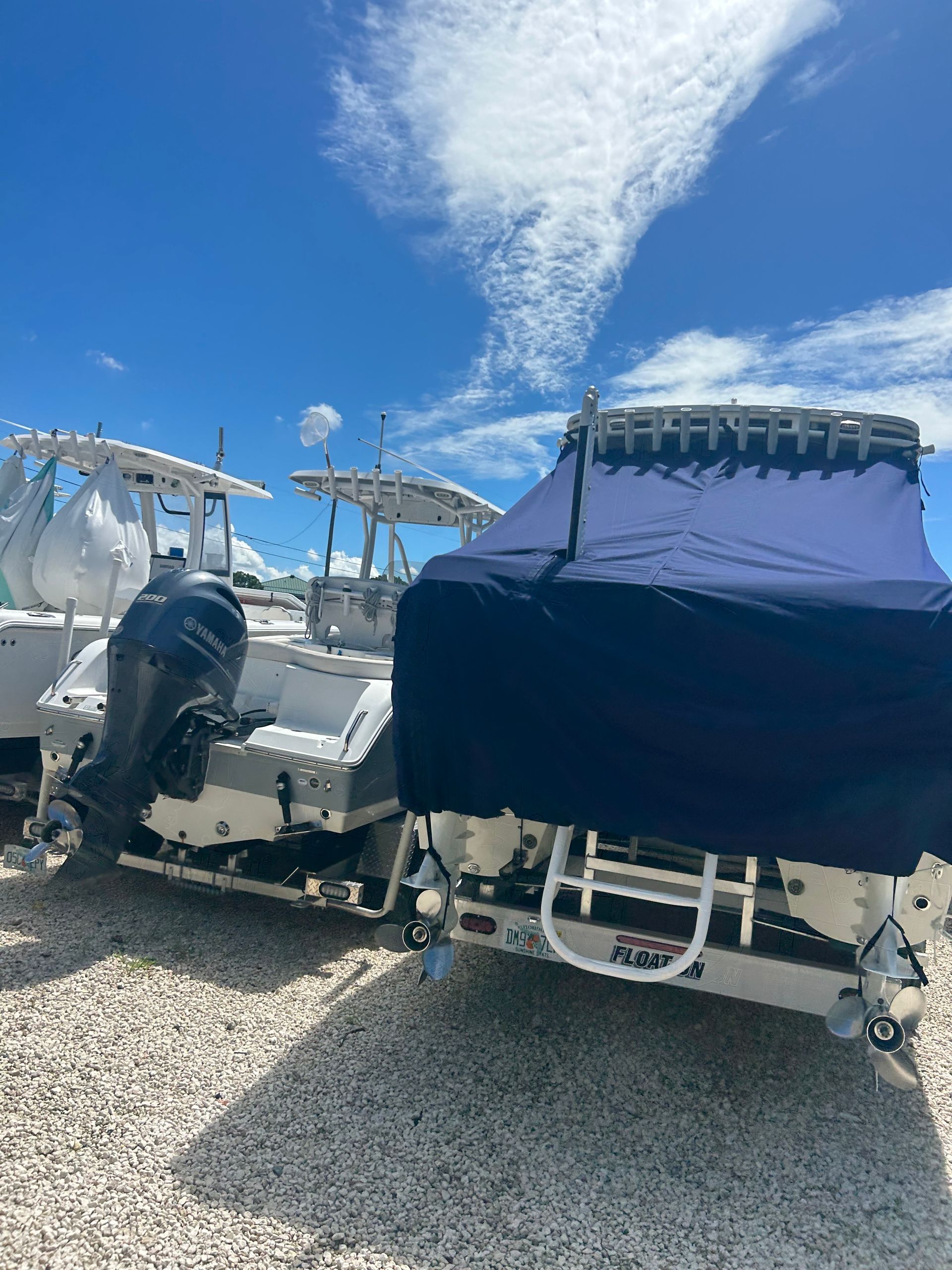 Boats on trailers, blue skies, white hulls, one with a blue cover.