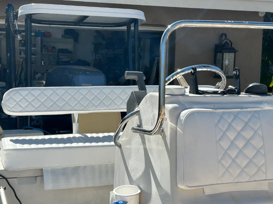 White boat interior with diamond-stitched cushions, stainless steel railing, and a golf cart in the background.