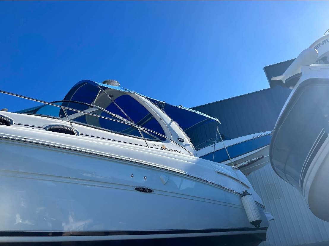 White motorboat with blue canvas top, docked on a sunny day.