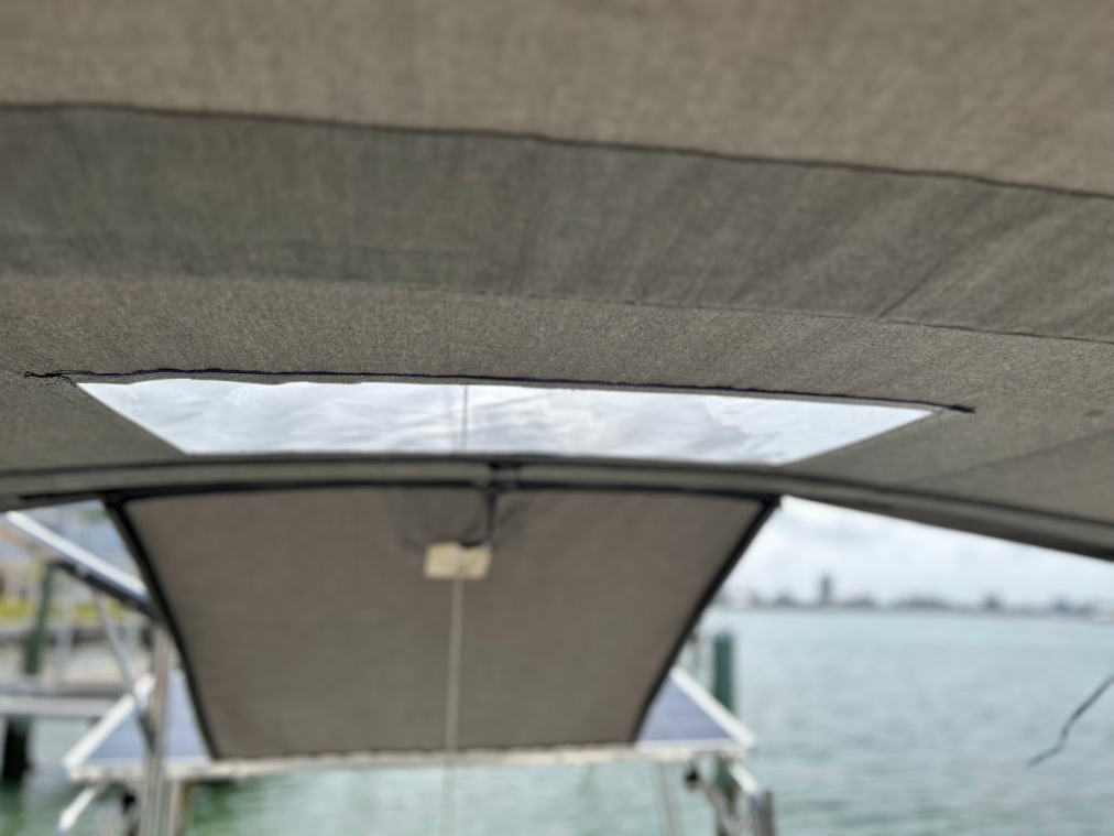 Interior view of a boat's canopy, showing a translucent panel and the ocean in the background.
