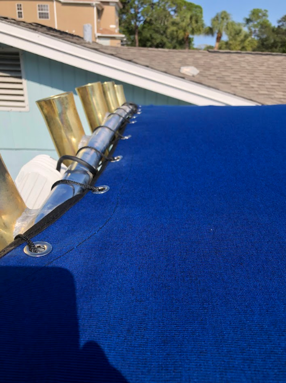 Blue awning with brass fixtures, near a house with a tan exterior.