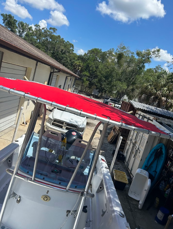 Boat with a red canopy, parked outside on a sunny day.